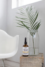 lem love room & body mist by Really Great Goods on wooden crate with plant in glass vase and white modern chair